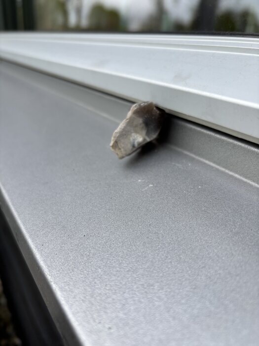 En sten placerad mellan fönsterblecket och listen på ett treglasfönster för att minska värmespänningen och knäppande ljud.