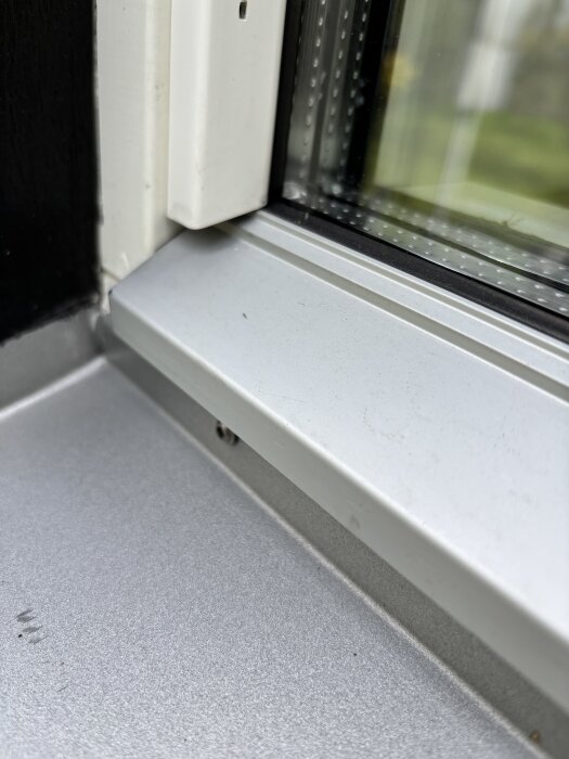 Närbild på treglasfönster med en metallfönsterbräda, där värmespänning uppstår vid solljus och orsakar ljudproblem.