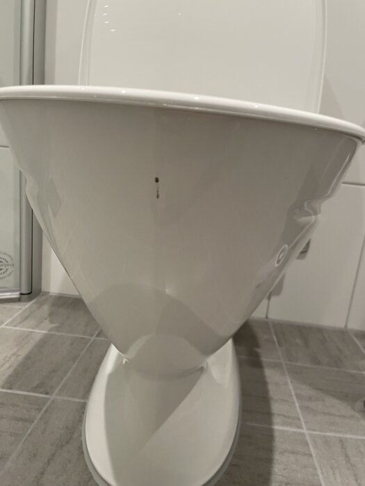 Toalettstol med en rostfläck inuti och skrapmärken på emaljen på utsidan.