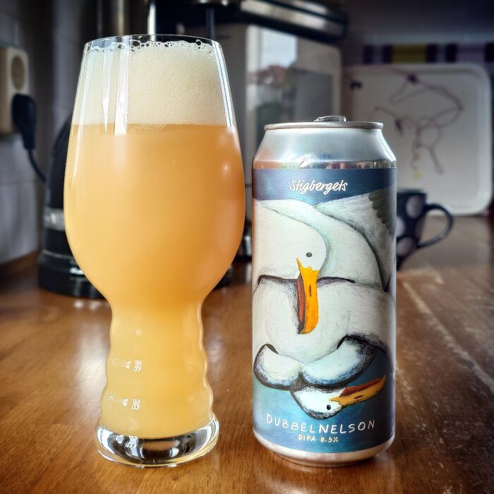 Ett glas med grumlig öl bredvid en burk Stigbergets Dubbelnelson DIPA, med etikett föreställande måsar.