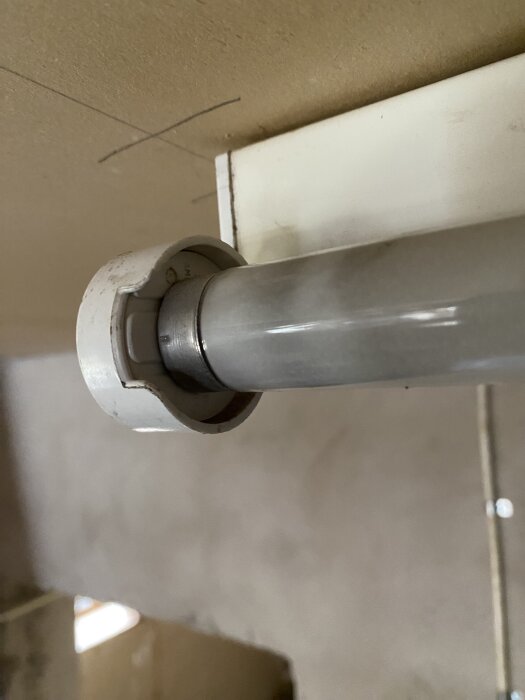 Gammal lysrörsarmatur med fastklämt rör, synligt från sidan, monterat under ett tak.