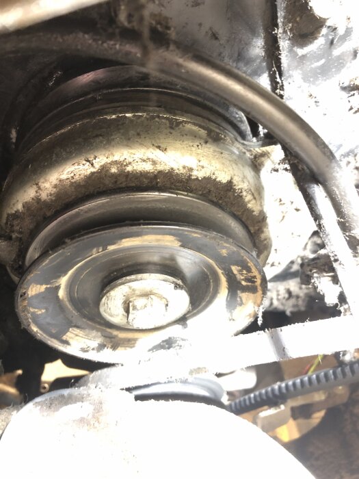 Närbild av ett remhjul på en åkgräsklippare Stiga Park 220, med drivrem och kabel i vägen för demontering.