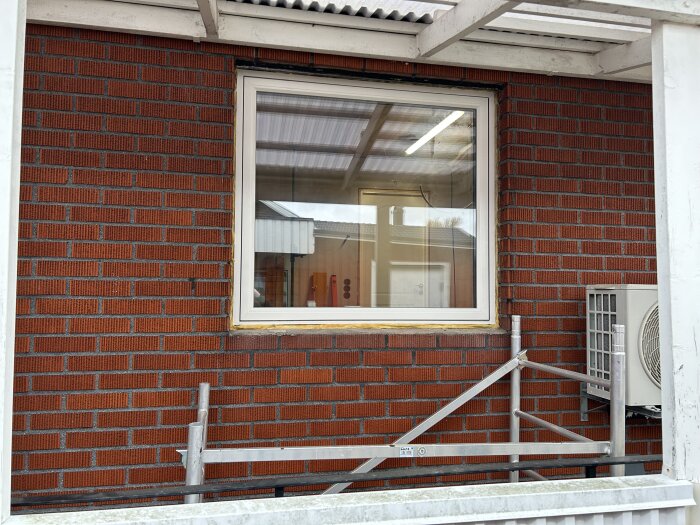 Nytt fönster installerat i röd tegelfasad, med byggställning framtill.