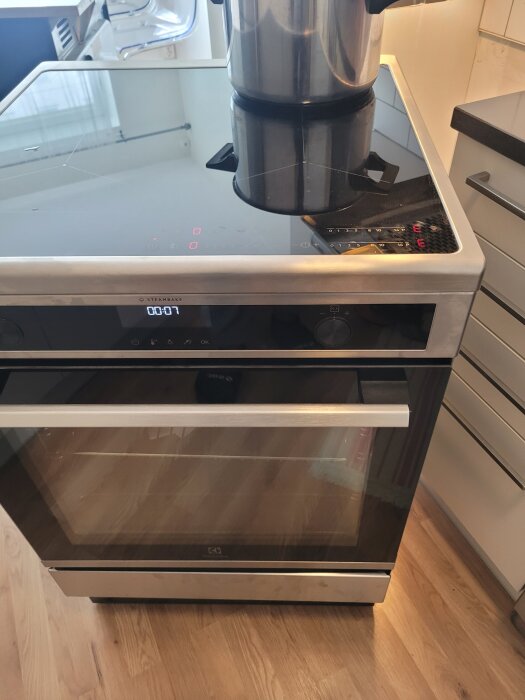 Induktionsspis från Electrolux med en kastrull på vänster platta, digital display visar tid. De två högra plattorna fungerar inte. Modell LKI66890SX.