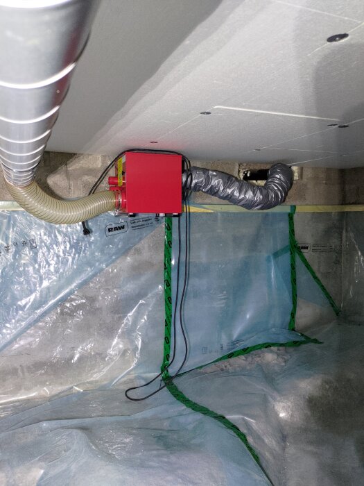 Röd avfuktare med slangar i krypgrund. Omgiven av plastfolie och cellplast i taket. Diskussion om brandskydd med lätt material.