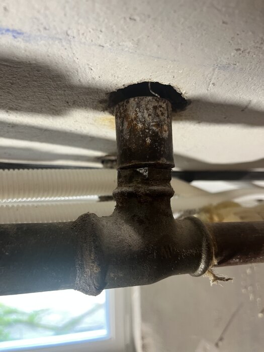 Gammalt järnrör med rostig t-kopplingsmutter, del av ett radiatorrör som behöver pluggas. Envis mutter som är svår att lossa.