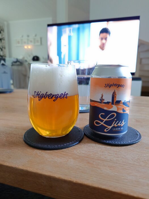 Ölglas och burk av Stigbergets Ljus lager på ett bord framför en TV.