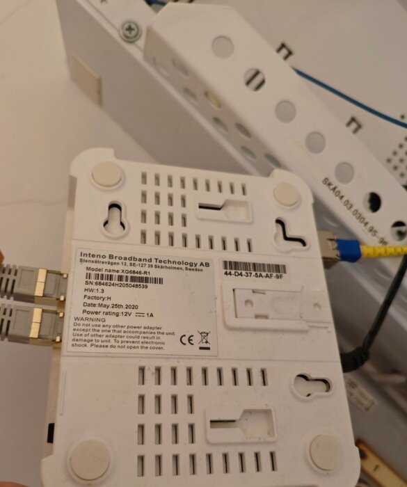 Modem från Inteno Broadband Technology AB med etikettdetaljer och anslutna kablar.