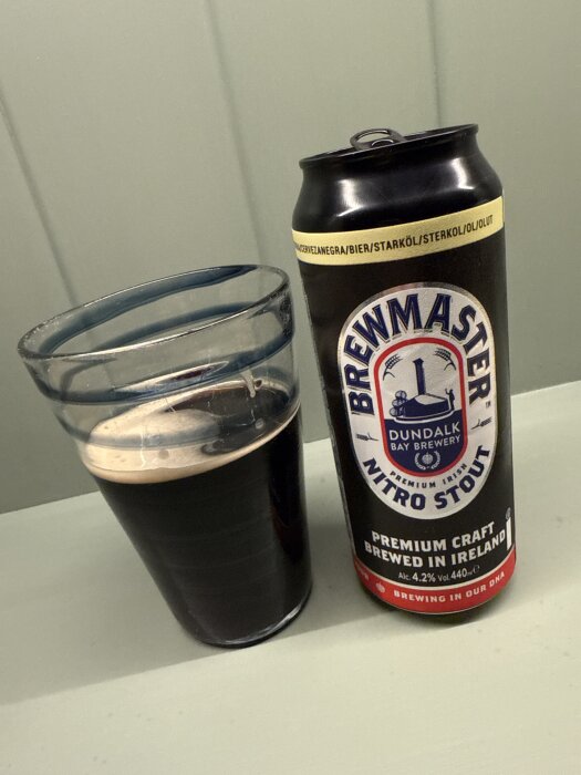 Brewmaster Nitro Stout-burk och halvtomt glas med stoutöl på ett bord.