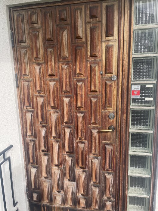 Gammal trädörr med slitage, monterad på ett funkishus från 1939, omgärdad av glasblock.