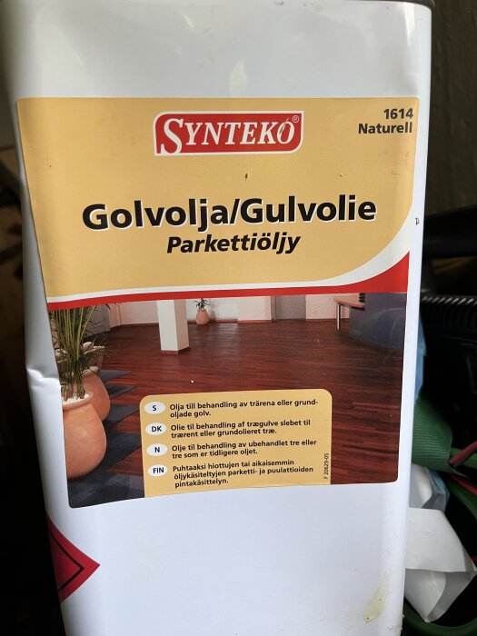 Förpackning av Synteko golvolja i färgen 1614 Naturell, med instruktioner för olika nordiska språk om användning för behandling av trägolv.