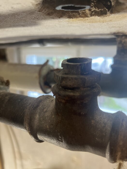 Rostigt rör med fast bussning och T-koppling under arbete; diskuteras kapning och uppvärmning för att få bort bussningen vid renovering.