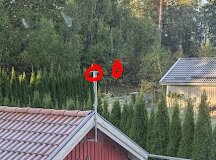 Två UAP-AC Mesh-enheter monterade på taket av ett garage mot en bakgrund av träd, markerade med röda cirklar.