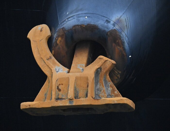 Ett kinesiskt drivankare av stål, rostfärgat, fastmonterat i ett mörkt skrov.