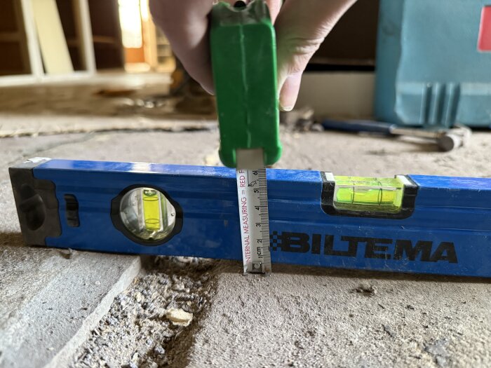 Vattenpass och måttband används för att mäta nivåskillnaden mellan kök och hall.