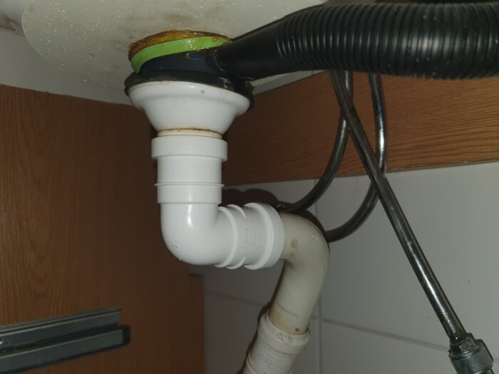 Röranslutningar under ett handfat, inklusive ett vitt rör och metallrör, med frågetecken kring närvaro av vattenlås.