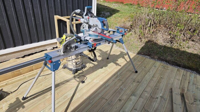 Ryobi cirkelsåg och Bosch kap- och gersåg på stativ utomhus, med Biltema-dammsugare placerad på altan.