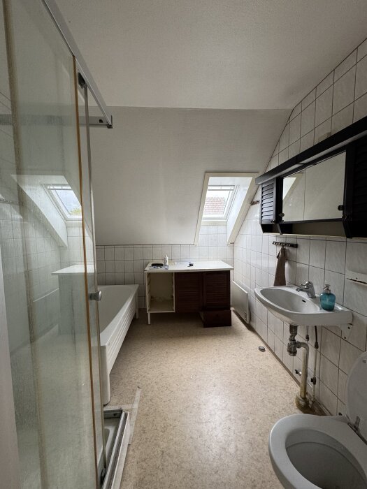 Badrum med duschkabin, badkar, och handfat. Spegelskåp saknas, vägghängd byrå borttagen. Förberett för badrumsrenovering.