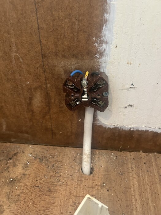 Brun Perilex-kontakt med blå och gul ledning monterad på vägg i sommarstuga, använd för spis och diskussion om induktion.