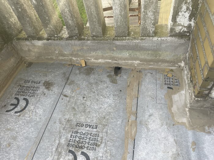 Balkonggolv med tätskiktsduk från Mira under installation, omgärdat av betong och tegel, med synligt applicerat lim.