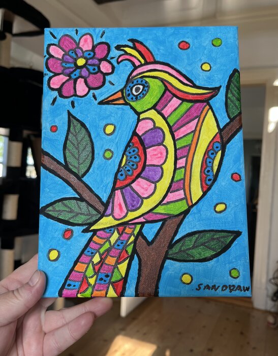 Färgglatt tecknad fågel på gren med blomma och blad, på blå bakgrund.