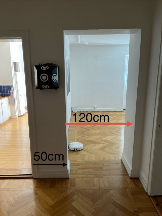 Öppen dörröppning mellan två rum med parkettgolv, röda pilen indikerar plats för önskad dörr (mått: 120 cm bredd, 50 cm djup).