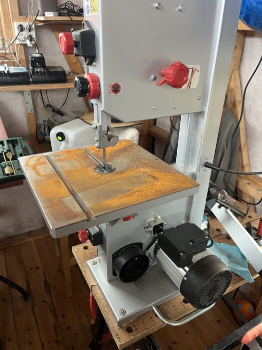 Rostig Metabo bandsåg med fuktangrepp i en verkstad på Öland, tecken på vattenskada, det visar sågens motor och arbetsbord.
