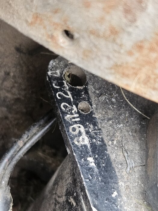 Nummerskylt på sliten startmotor i en åkgräsklippare, numret på skylten är delvis oläsligt.