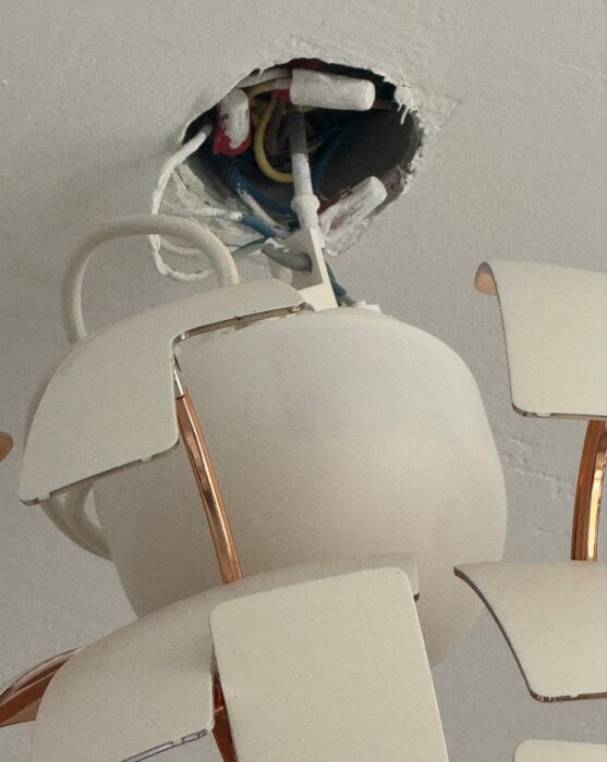 Lamputtag i tak med synliga kablar, där wago-kopplingar är installerade. Lampan hänger ner med en del av takets ledningar exponerade.