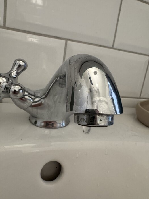 Kromad tvättställsblandare med korshandtag och texten "DANIEL".