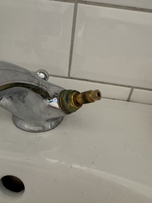 Kran med borttagen spak från tvättställsblandare, exponerad ventil synlig, söker hjälp med packningsbyte.
