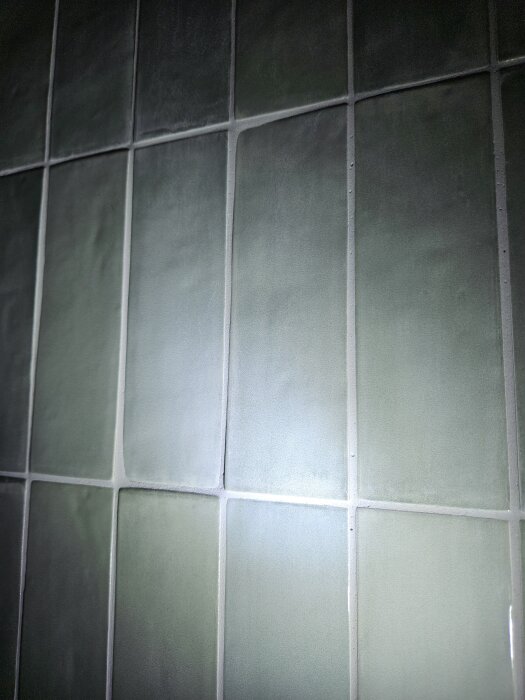 Gröna kakelplattor på en nyrenoverad badrumsvägg.