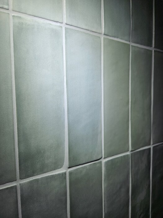 Gröna kakelplattor i nyrenoverat badrum.