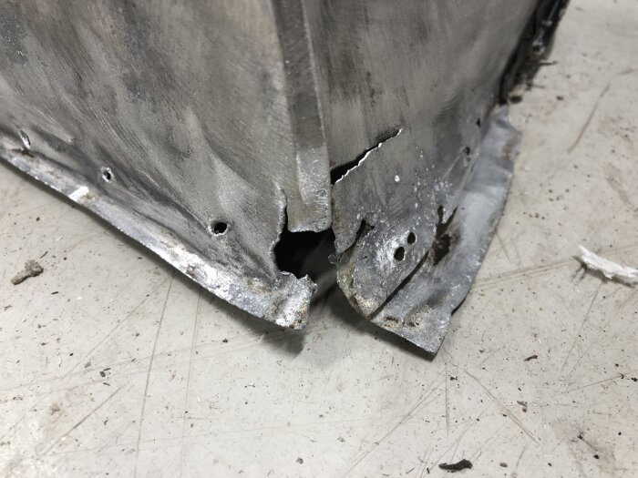 Skadat aluminiumhörn med rost och hål, del av en vagnsram under renovering.