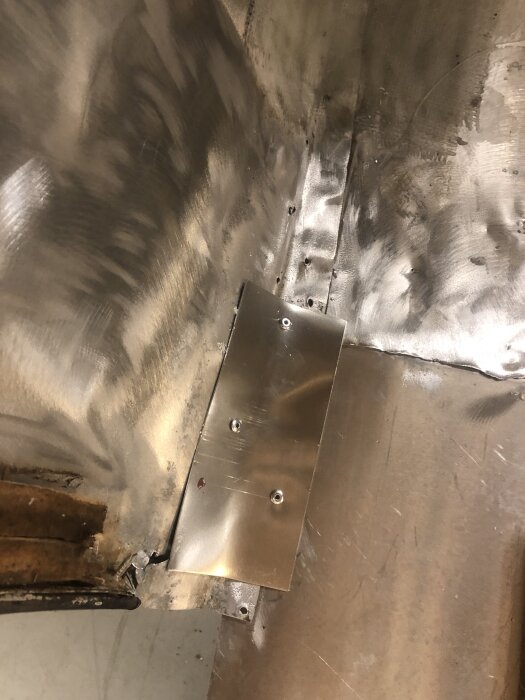 Aluminiumplåt fastnitat i ett hörn av husvagn, del av plastningsarbete för att förstärka vagnen.
