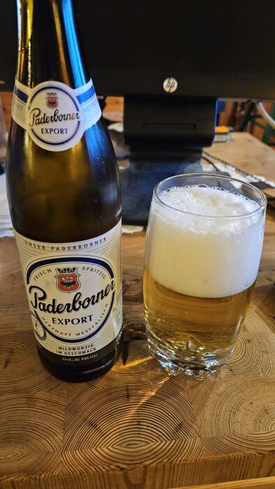 Flaska och glas med Paderborner Export-öl på ett träbord.
