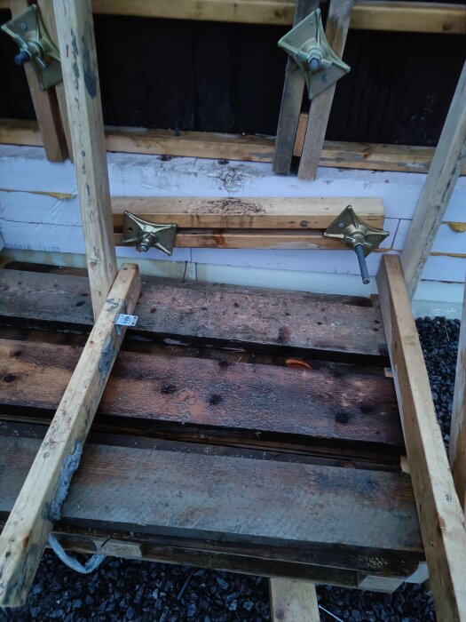 Träram med reglar och formstag monterade ovanpå cellplastskivor, synliga på en byggarbetsplats för betonggjutning.