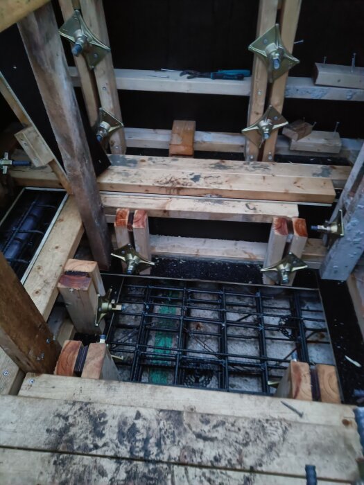 Byggkonstruktion med träformar, metallstag och isoleringsmaterial, del av gjutprocessen med formstag och hullingar på plats.