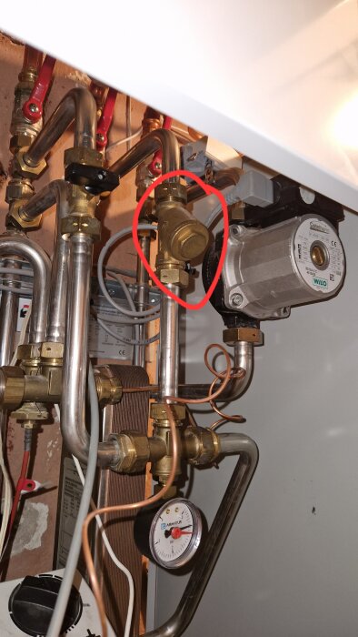 Returslinga för radiatorer med rörkopplingar och en plugg med sexkantsskalle inringad i rött, del av fjärrvärmesystem.