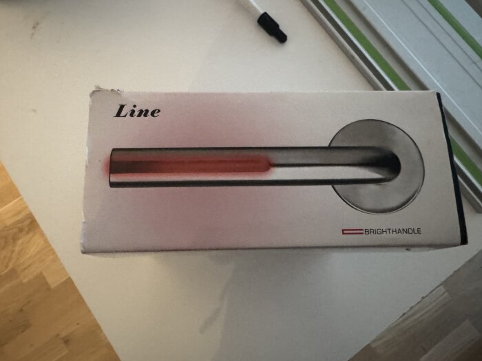 Kartong med texten "Line" och "BRIGHTHANDLE", visar stiliserat handtag.