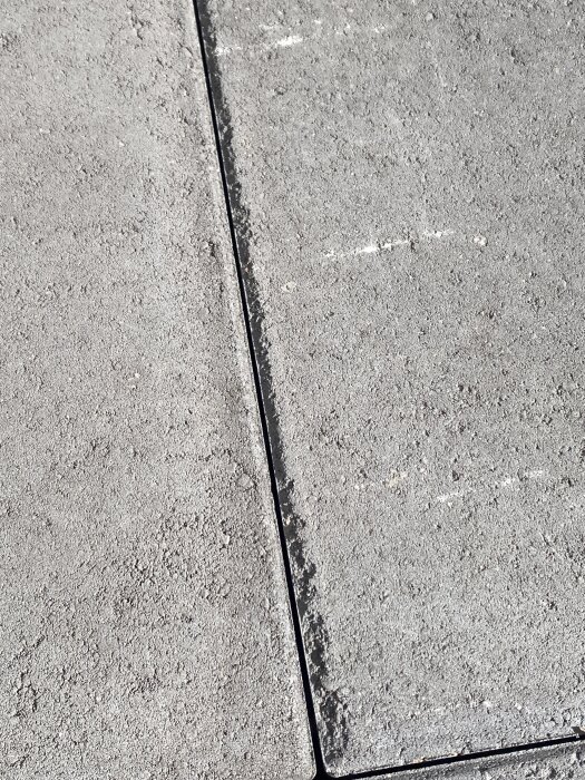 Närbild av grå betongplattor med en tydlig fog emellan dem.