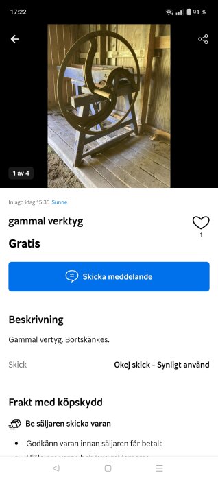 Gammalt verktyg med stor metallmekanism, kanske en gammal cirkelsåg, i trägolv och träväggsrum. Verktyget är rostigt och slitet.