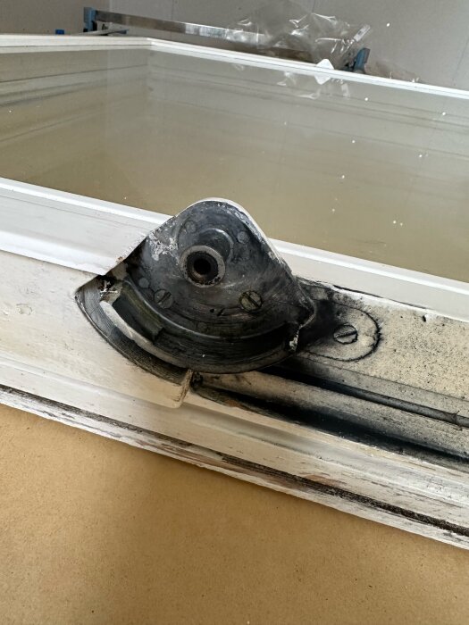 Bilden visar ett äldre Myresjö perspektivfönster från 60-talet med ett slitet beslag i närbild.