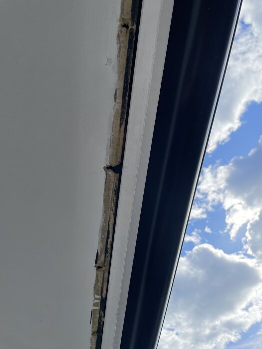 Skiva med skada och bräda borttagen, med himmel i bakgrunden.