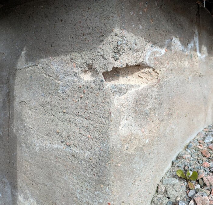 Skadad hussockel från tidigt 80-tal visar sprickor och erosion. Slipade ytor, kratrar och vita missfärgningar syns. Behöver lagas och slammad yta återskapas.