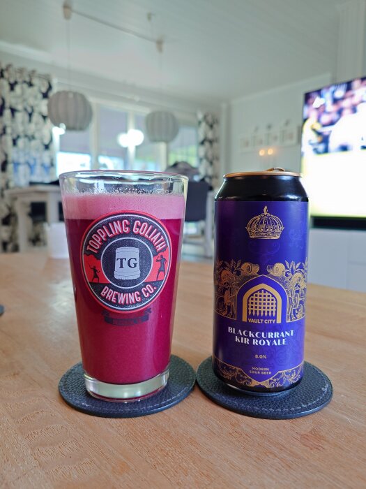 Ett glas med syrlig svartvinbärsöl och en burk från Vault City på ett bord, bakgrunden visar en ljus inomhusmiljö.