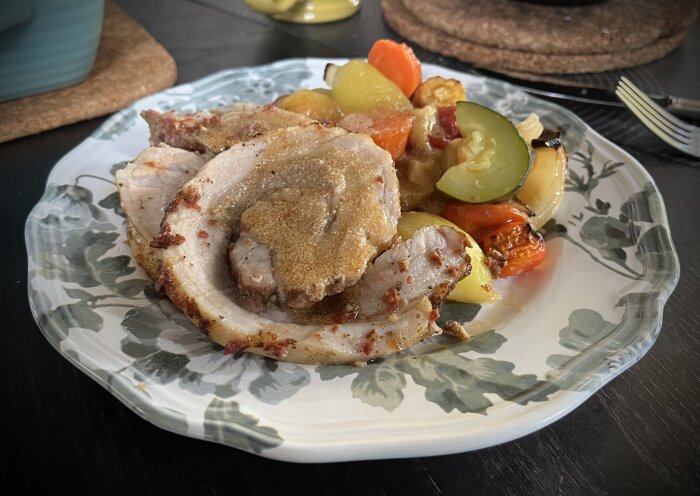 Porchetta serverad med ugnstekta grönsaker som potatis, morot, palsternacka, squash, vitlök, lök, paprika och körsbärstomater på en tallrik.
