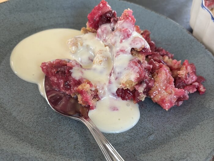 Smulpaj med röda krusbär serverad med vaniljsås på en tallrik.