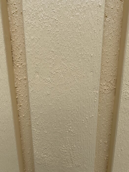 Närbild av nymålad fasad med ojämn yta och droppar, vilket indikerar dålig målningsteknik.