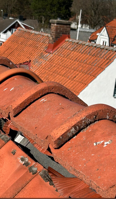 Rött tak täckt med takpannor, delar av taket ser ojämnt ut, vilket tyder på potentiella justeringsbehov.